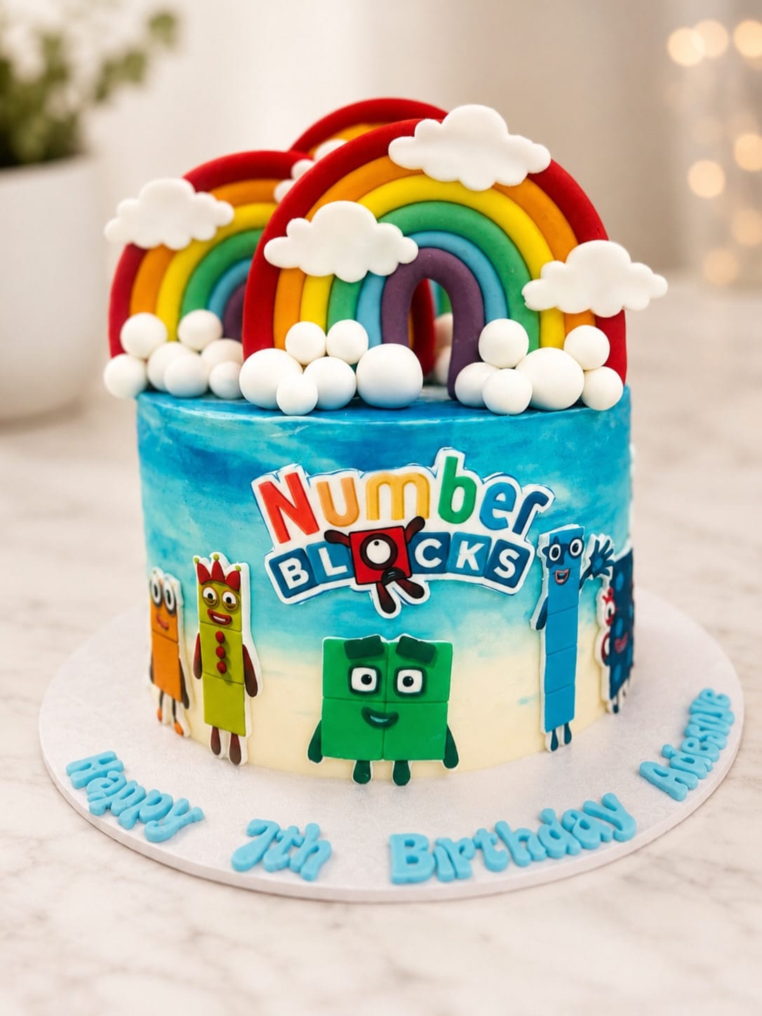 Children's birthday cake in sky blue buttercream with a fondant rainbow, clouds and character toppers