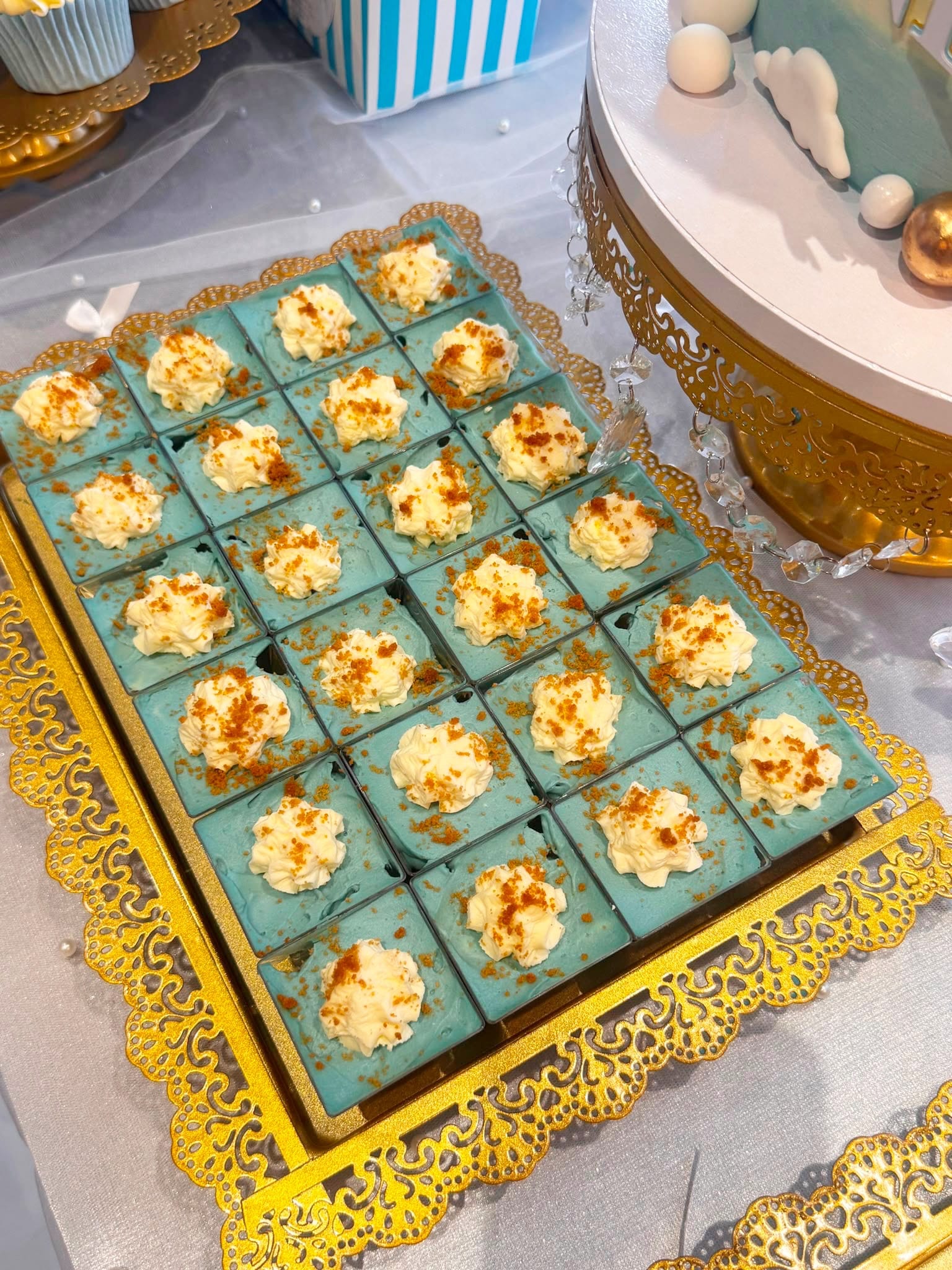 Tray of mint coloured dessert squares topped with piped cream rosettes