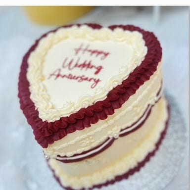 Red velvet heart cake with cream piping and hand-piped wedding anniversary lettering
