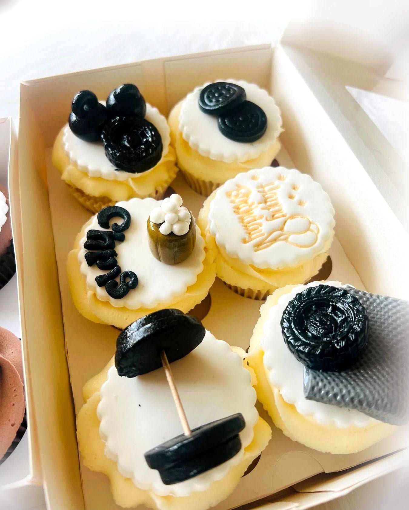 Black & Gold Luxury Cupcakes by SpongyBakes — A box of ivory cupcakes finished with black and gold fondant detailing.