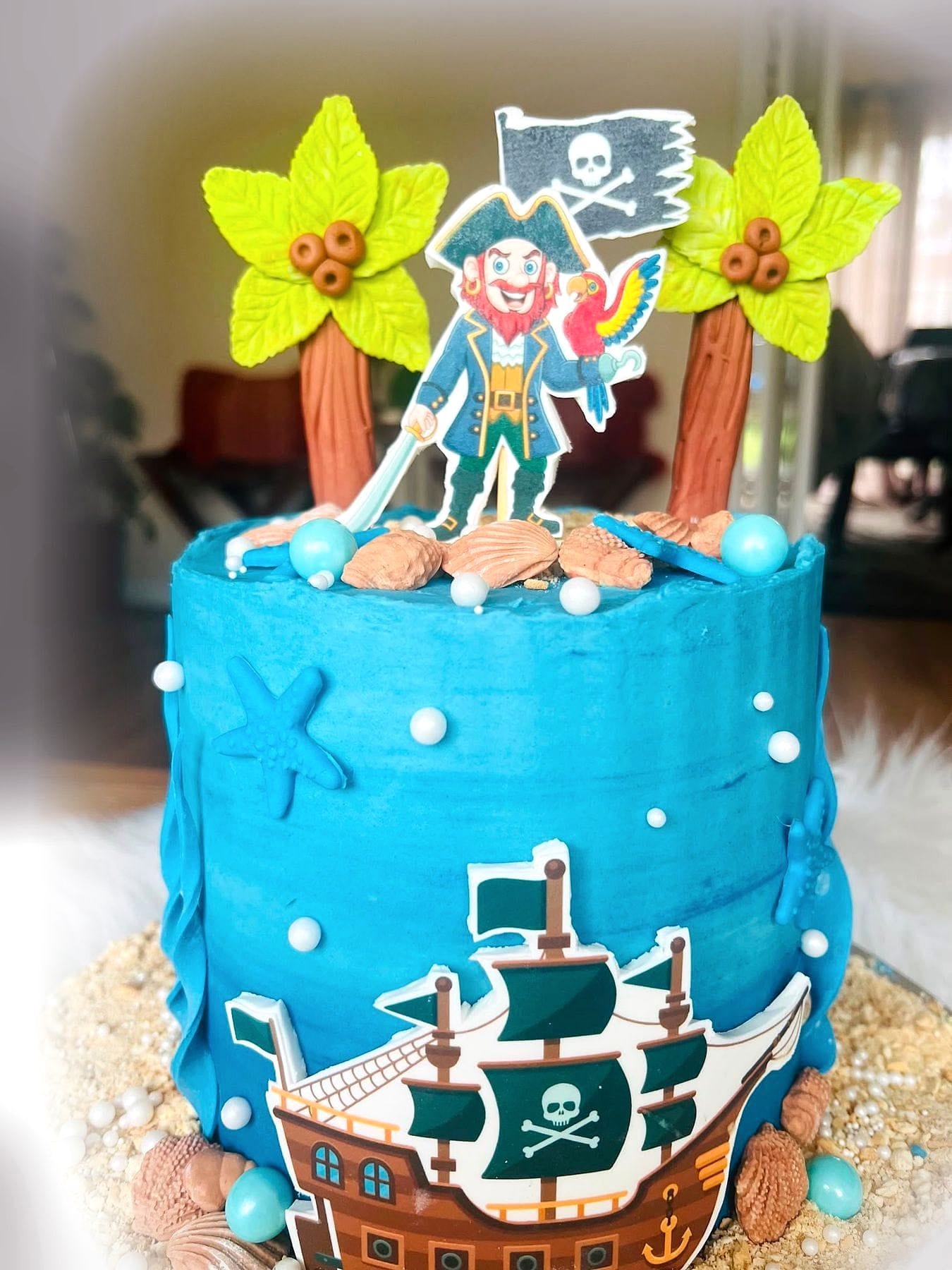 Pirate Ship Birthday Cake by SpongyBakes — An ocean-blue cake with a hand-made pirate ship, palm trees and a pirate topper.