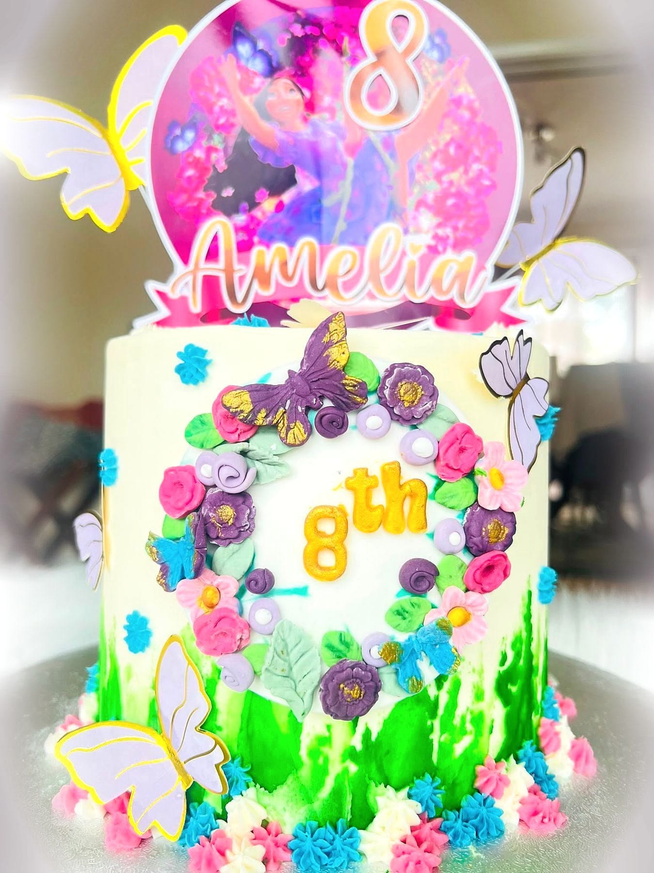 Fairy Garden Birthday Cake by SpongyBakes — A cake covered in piped flowers and butterflies with a fairy topper.