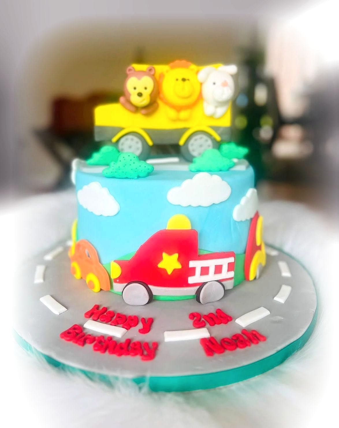 Little Traffic Jam Birthday Cake by SpongyBakes — A sky-blue cake with a fondant road, fire engine and animal train toppers.