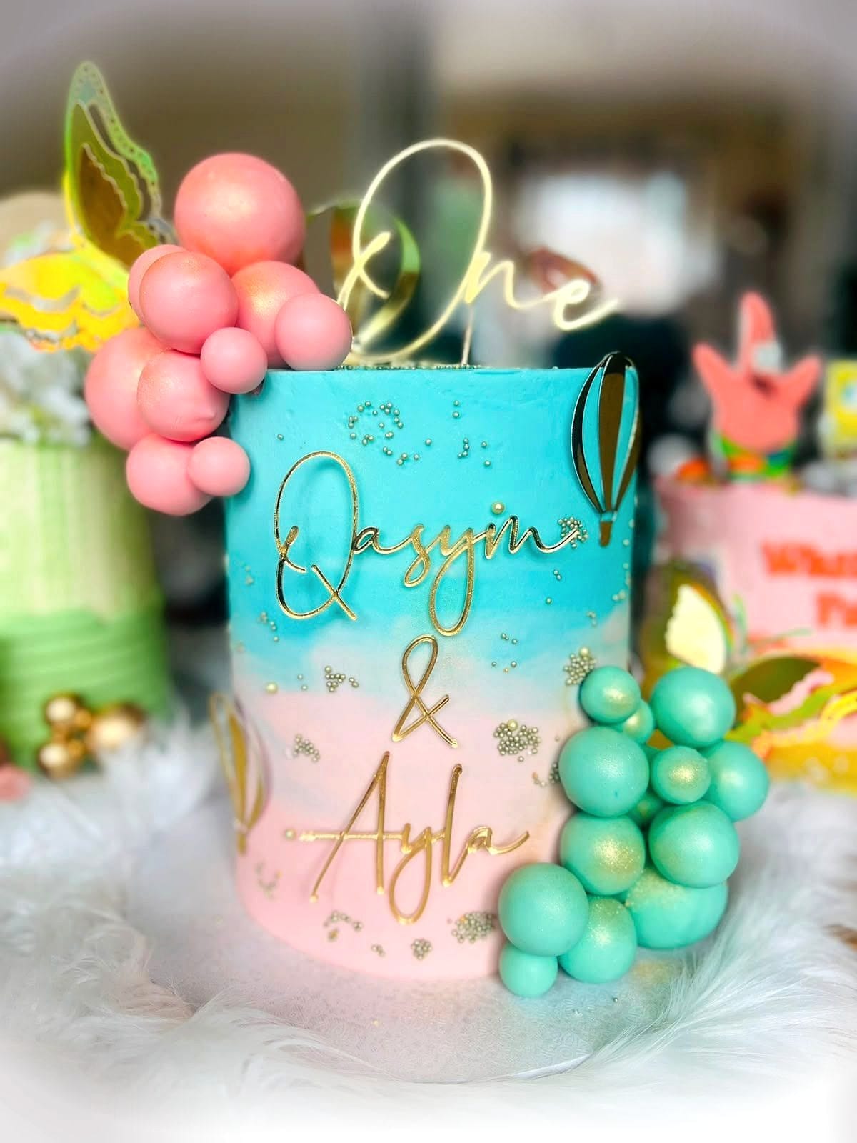 Pastel Balloon First Birthday Cake by SpongyBakes — A pastel ombré cake with a chocolate balloon cluster and gold lettering.