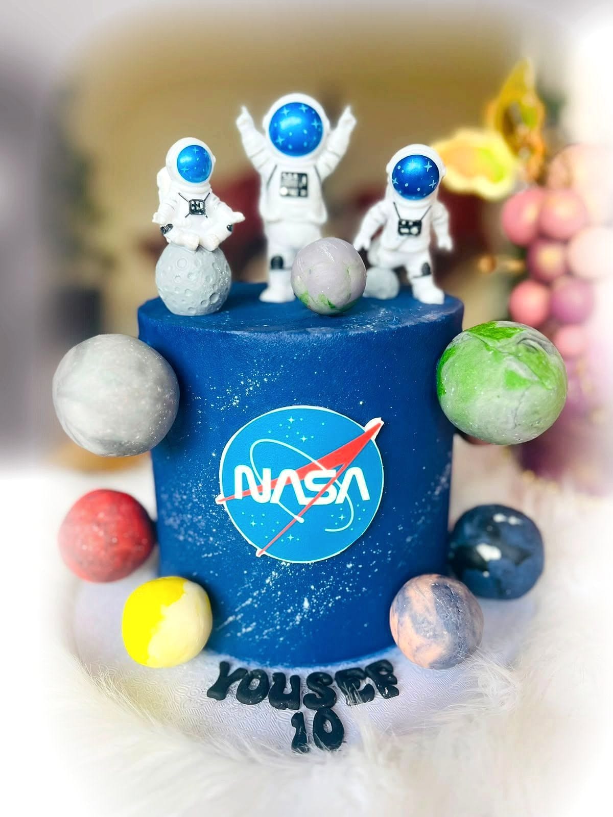 Space Explorer Birthday Cake by SpongyBakes — A deep blue galaxy cake with hand-painted planets and astronaut toppers.