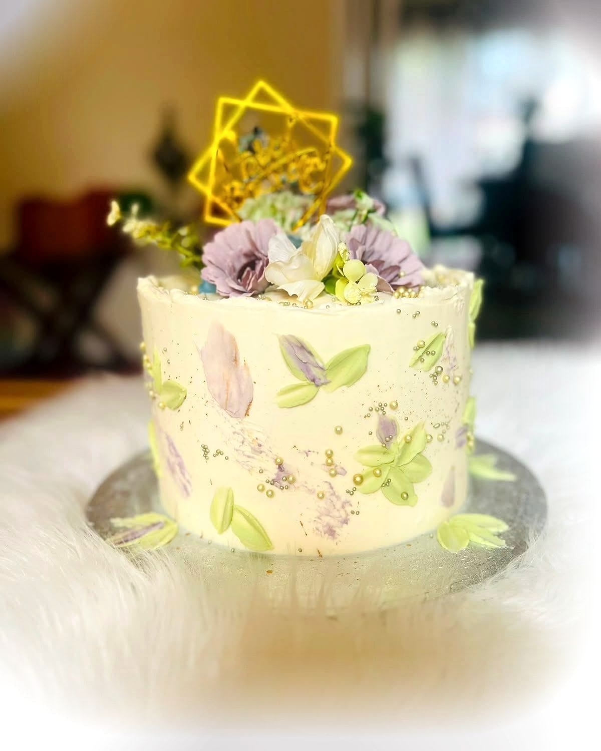 Pressed Flower Buttercream Cake by SpongyBakes — A soft ivory buttercream cake pressed with edible flowers and foliage.