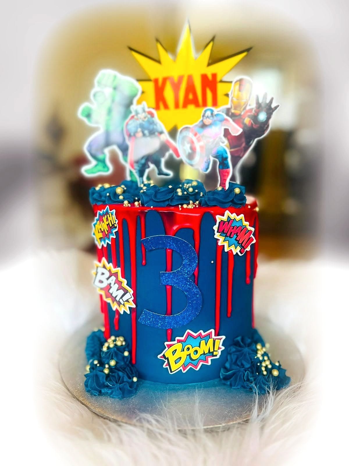 Comic Burst Birthday Cake by SpongyBakes — A navy and red cake with comic blast panels, gold drips and character toppers.