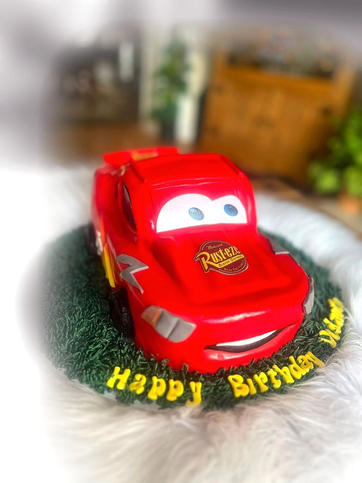 Red Racing Car Birthday Cake by SpongyBakes — A sculpted red racing car on a piped grass board with fondant lettering.
