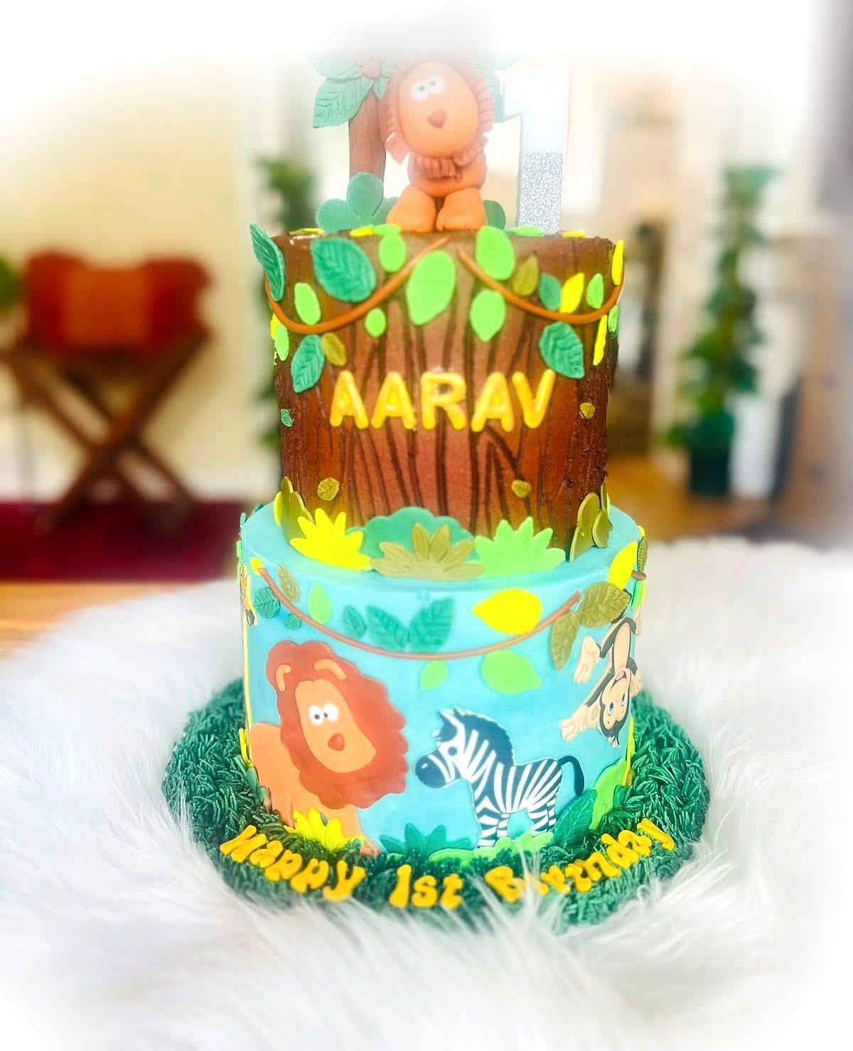 Safari First Birthday Cake by SpongyBakes — A two-tier safari cake with a carved tree, hand-painted animals and a monkey topper.