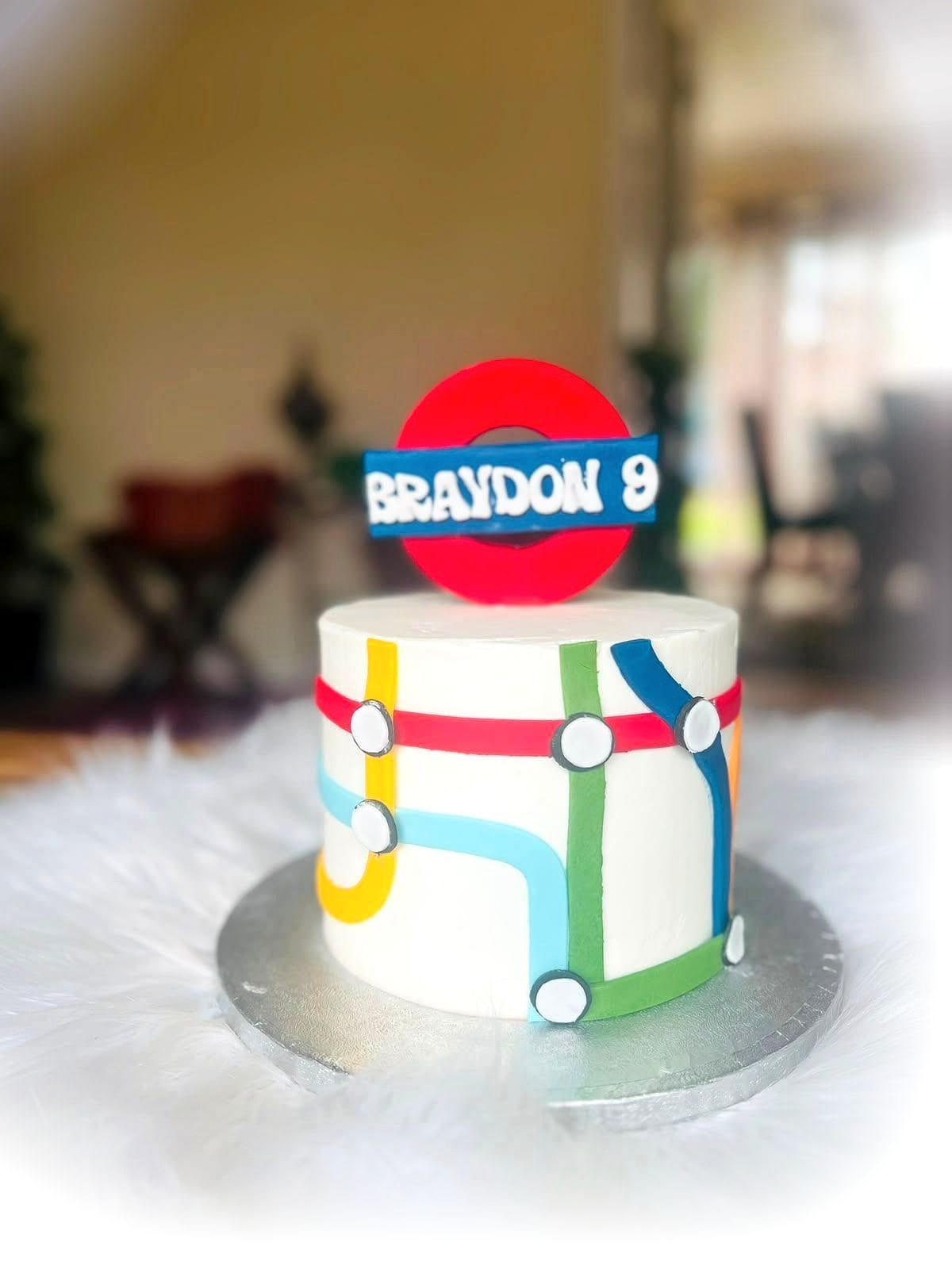 Sports Birthday Cake by SpongyBakes — A white cake with piped sports detailing and a bold printed name topper.