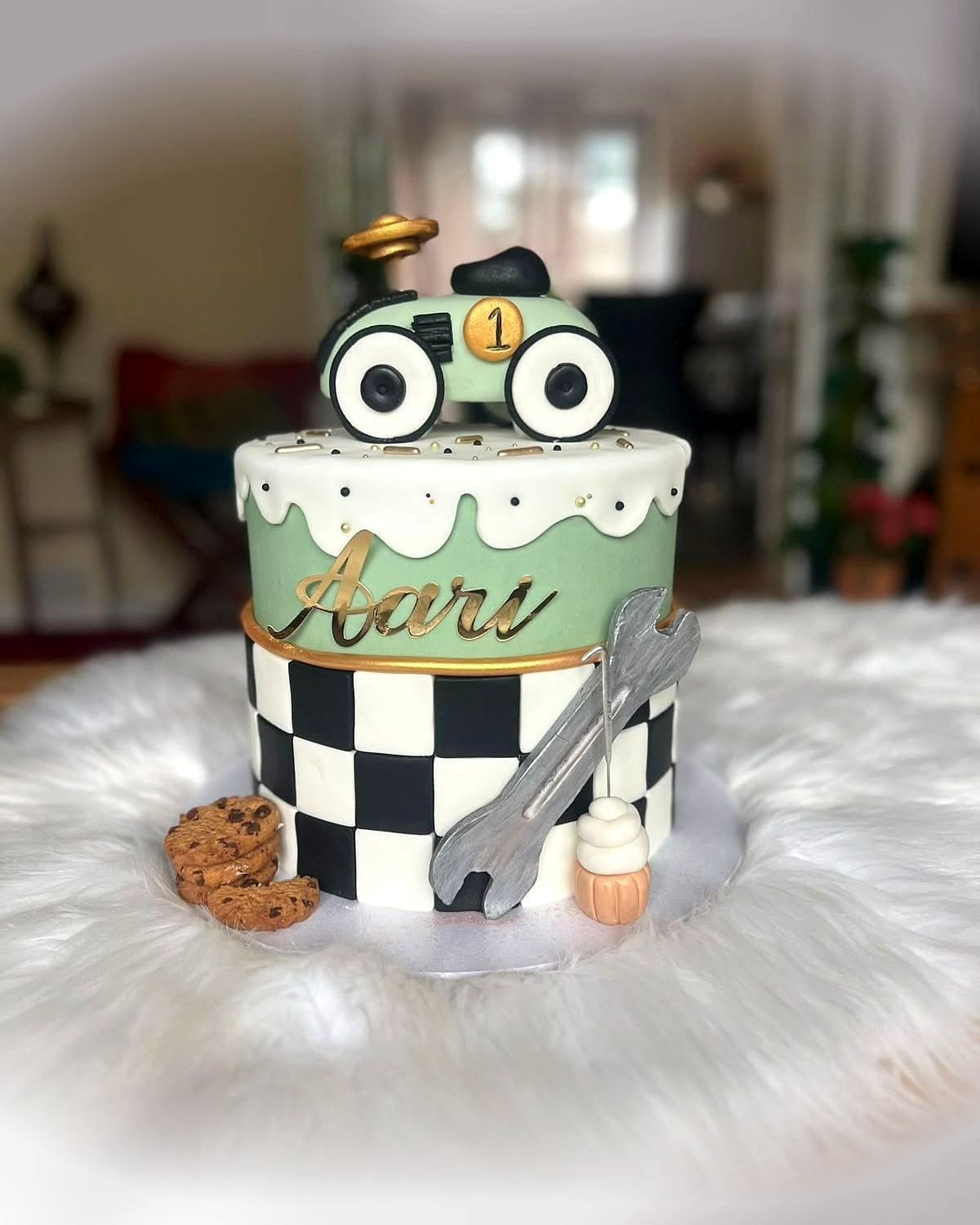 Little Mechanic Birthday Cake by SpongyBakes — A chequered cake with hand-modelled tools, a car topper and a piped name.