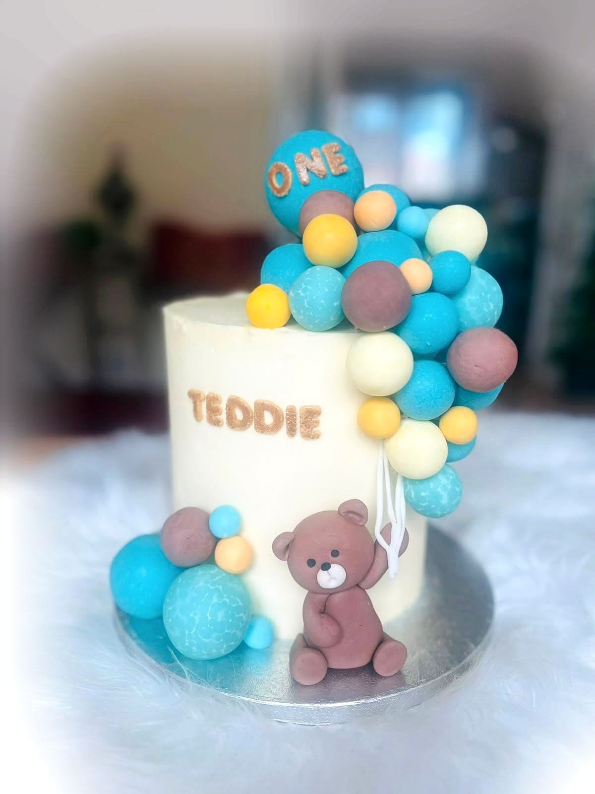 Teddy Balloon First Birthday Cake by SpongyBakes — An ivory cake with a pastel balloon cluster and a hand-modelled teddy.