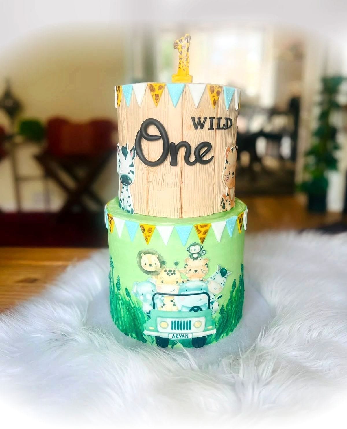 Wild One First Birthday Cake by SpongyBakes — A two-tier cake with a carved wood-effect top tier and a hand-painted safari base.